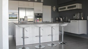 A modern kitchen with white cabinetry, stainless steel appliances, and a central island with bar stools.