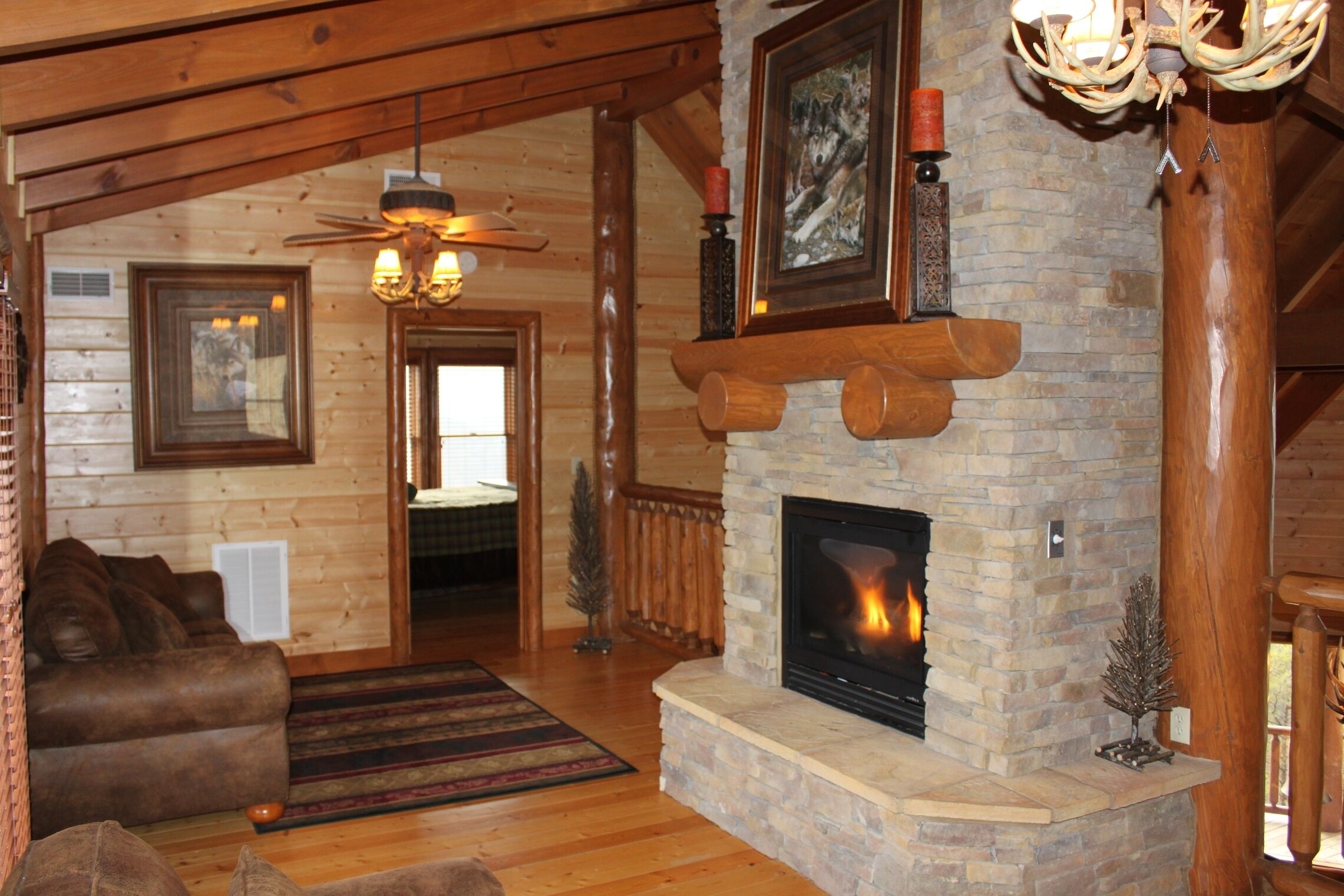 L’intérieur d’un chalet confortable, avec une cheminée, des meubles en bois et un ventilateur de plafond.