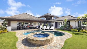 Una casa de dos pisos con piscina, mobiliario exterior y un jardín bien cuidado.