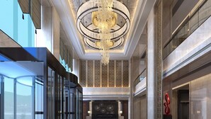 Een ruime lobby met een grote kroonluchter, een receptiebalie en een modern design.