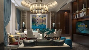 Een moderne hotel lobby met een eetgedeelte, een groot schilderij, een kroonluchter en een televisiescherm.