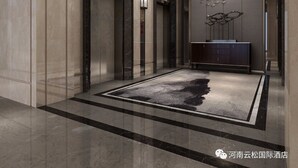 Een moderne hotellobby met een grote kroonluchter, een centraal console tafeltje en een kamerbreed tapijt met dessin.