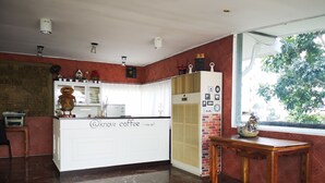 A kitchen with a white island, a refrigerator, and a window with a view of trees. - Daoreang  Resort 2 (Thanyaburi)