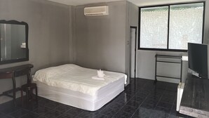 A bedroom with a bed, a desk, a chair, a TV, and a window with floral curtains. - Daoreang  Resort 2 (Thanyaburi)