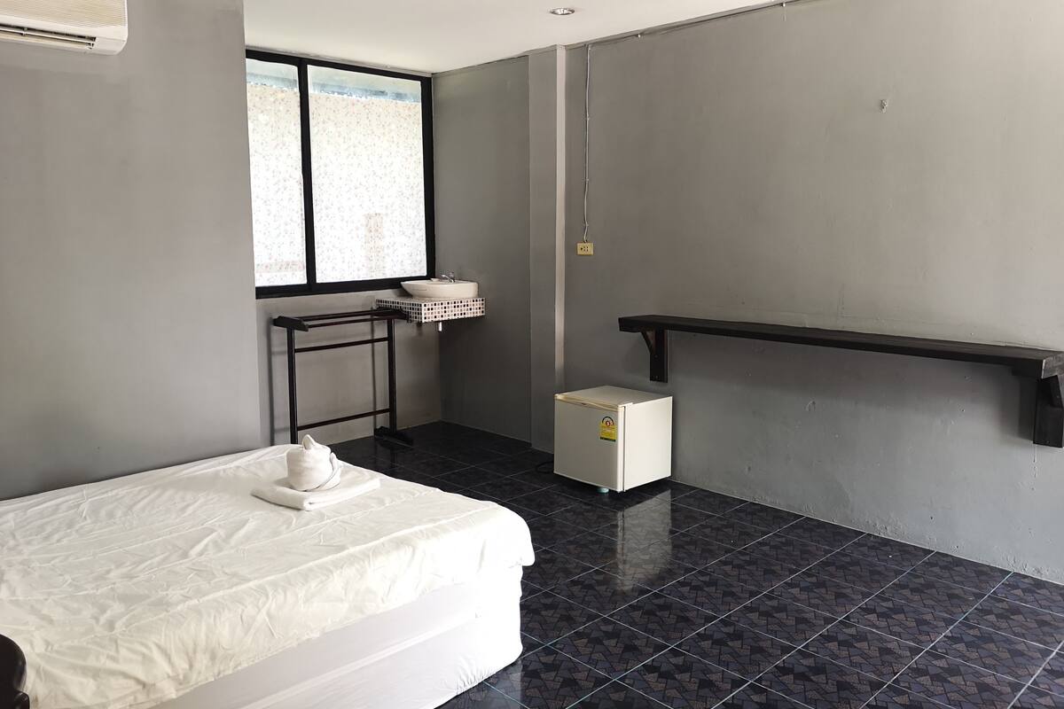A room with a bed, a small sink, a heater, and a window with a view.