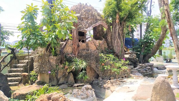 A garden with a stone wall, a small pond, and various plants. - Daoreang  Resort 2 (Thanyaburi)