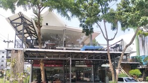 A modern building with a covered outdoor seating area, a staircase, and a car parked nearby. - Daoreang  Resort 2 (Thanyaburi)