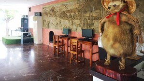 A room with a large bear statue on a pedestal, a mural on the wall, a desk with a computer, and a green cushioned seating area. - Daoreang  Resort 2 (Thanyaburi)
