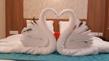 Una cama con dos toallas con forma de cisne y una rosa roja en el centro.