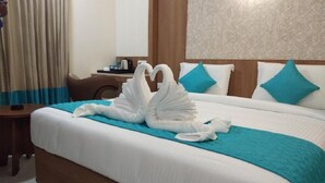 Una habitación de hotel con una cama bien hecha, cabecero de madera y un escritorio con hervidor.