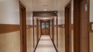 Un pasillo largo y estrecho con puertas de madera a ambos lados y suelo de baldosas.