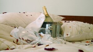 A bed with a champagne bottle, glasses, and scattered rose petals. - Hotel Zovko (Sibinj)