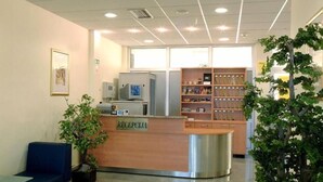 A reception area with a wooden desk labeled "RECEPCIA," a blue bench, and a bookshelf with various items. - Hotel Zovko (Sibinj)