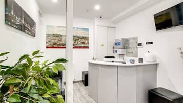 A modern reception area with a counter, seating, and a plant.