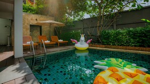Una piscina con juguetes inflables, sillas de descanso y una sombrilla.