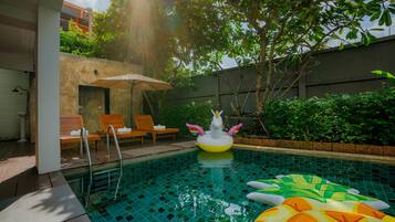 Alberca al aire libre, sombrillas en la alberca y camastros