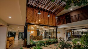 Un espacio interior moderno con recepción, asientos y plantas en macetas.