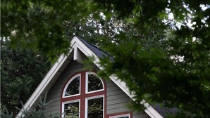 A house with a large central window, a red porch, and a wooden deck.
