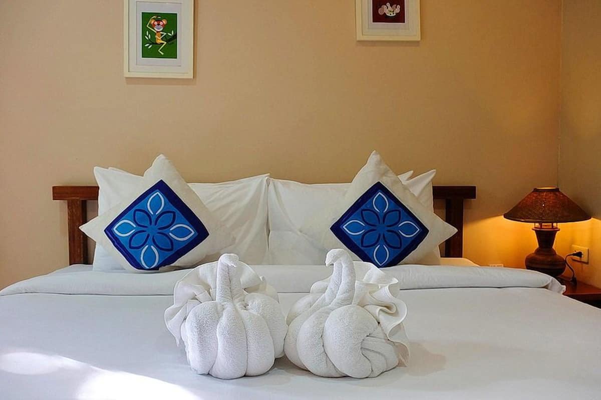 A neatly made bed with two decorative pillows, a lamp on the side, and a framed picture on the wall.