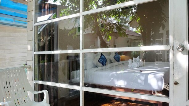 A room with a bed, a white chair, and a glass door leading outside. - Reera Resort (Hua Hin)
