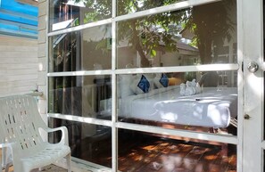 A room with a bed, a white chair, and a glass door leading outside. - Reera Resort (Hua Hin)