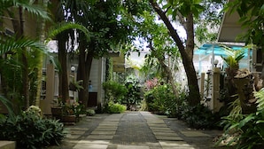 A paved pathway leading through a lush garden with various plants and trees. - Reera Resort (Hua Hin)