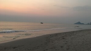 A beach with a boat in the distance and a mountain in the background. - Reera Resort (Hua Hin)