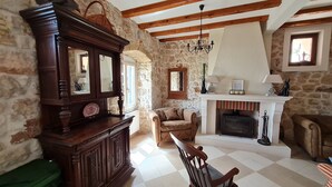 A rustic room with exposed wooden beams, a stone wall, a fireplace, and a rocking chair. - 16th century villa Filomena, panoramic sea views, walking distance to Old Town (Dubrovnik)