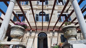 A stone building with a covered entrance, steps leading up to it, and potted plants on either side. - 16th century villa Filomena, panoramic sea views, walking distance to Old Town (Dubrovnik)