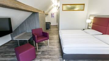 Ein modernes Hotelzimmer mit Bett, Schreibtisch, Stuhl und Fernseher.