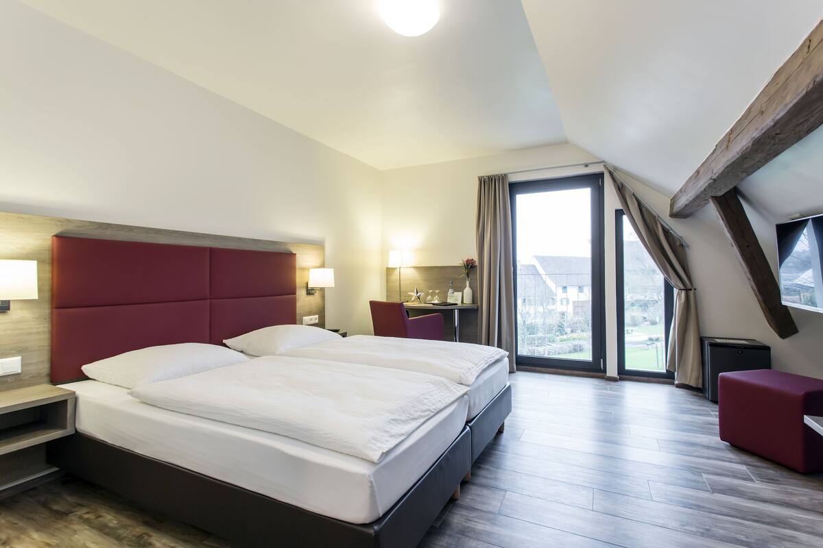 Ein modernes Hotelzimmer mit einem großen Bett, einem Schreibtisch und Blick ins Freie.