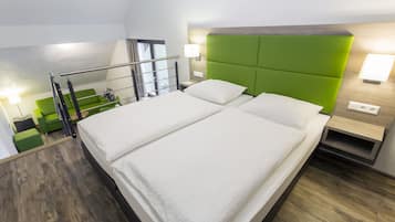 Una habitación de hotel moderna con una cama grande, cabecera tapizada en verde y un balcón con sofá verde.