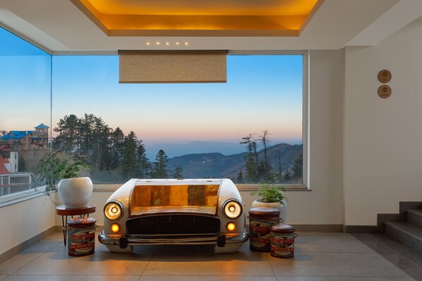 A modern interior with a vintage car model, large windows, and a view of a mountainous landscape.