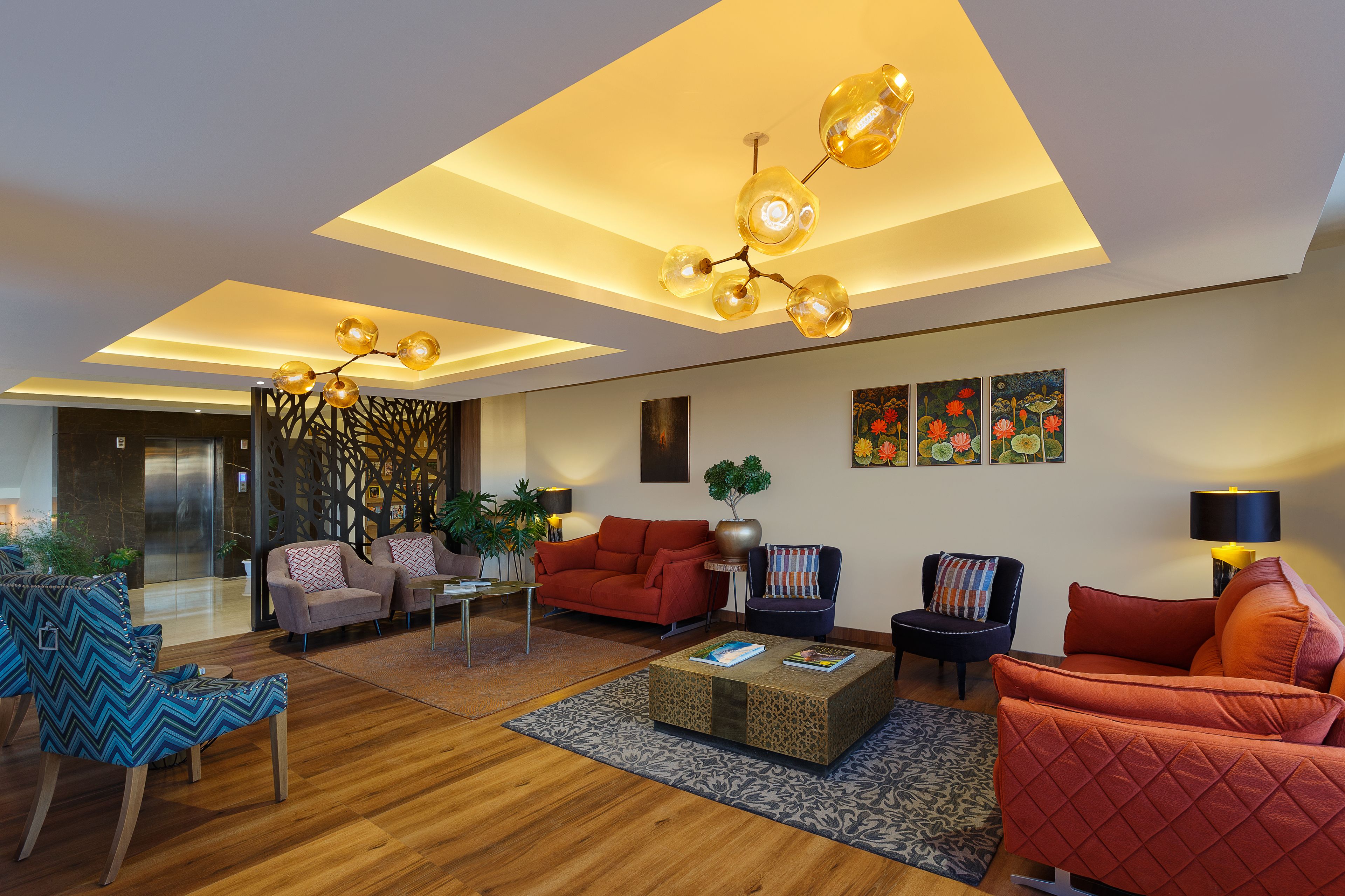 Uma sala de estar moderna com piso de madeira, uma mesa de centro e assentos, incluindo um sofá vermelho e uma poltrona azul.