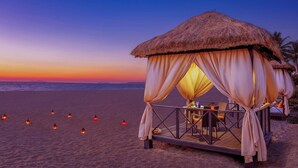 A beach hut with a thatched roof, draped curtains, and a wooden deck. - ITC Grand Goa, a Luxury Collection Resort & Spa, Goa (Cansaulim)