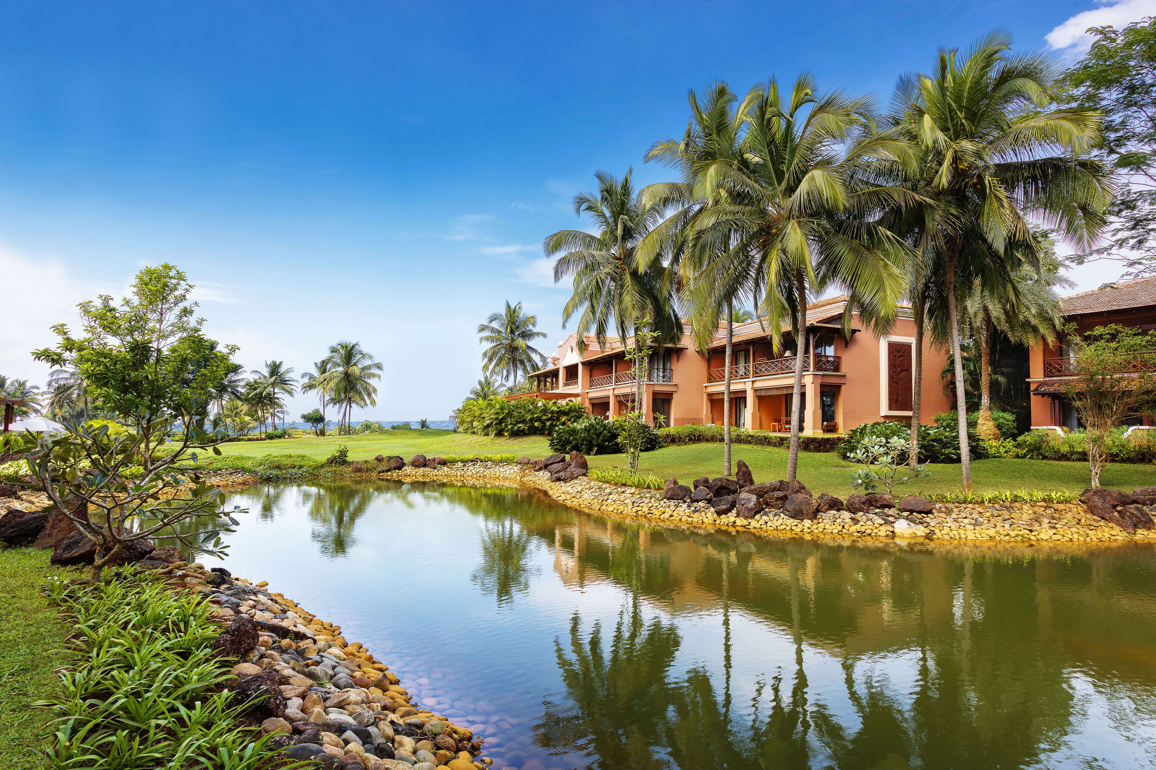 A resort with a pool, palm trees, and a building with balconies.