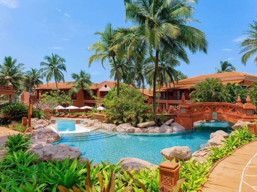 Un resort con piscina, palmeras y un puente.