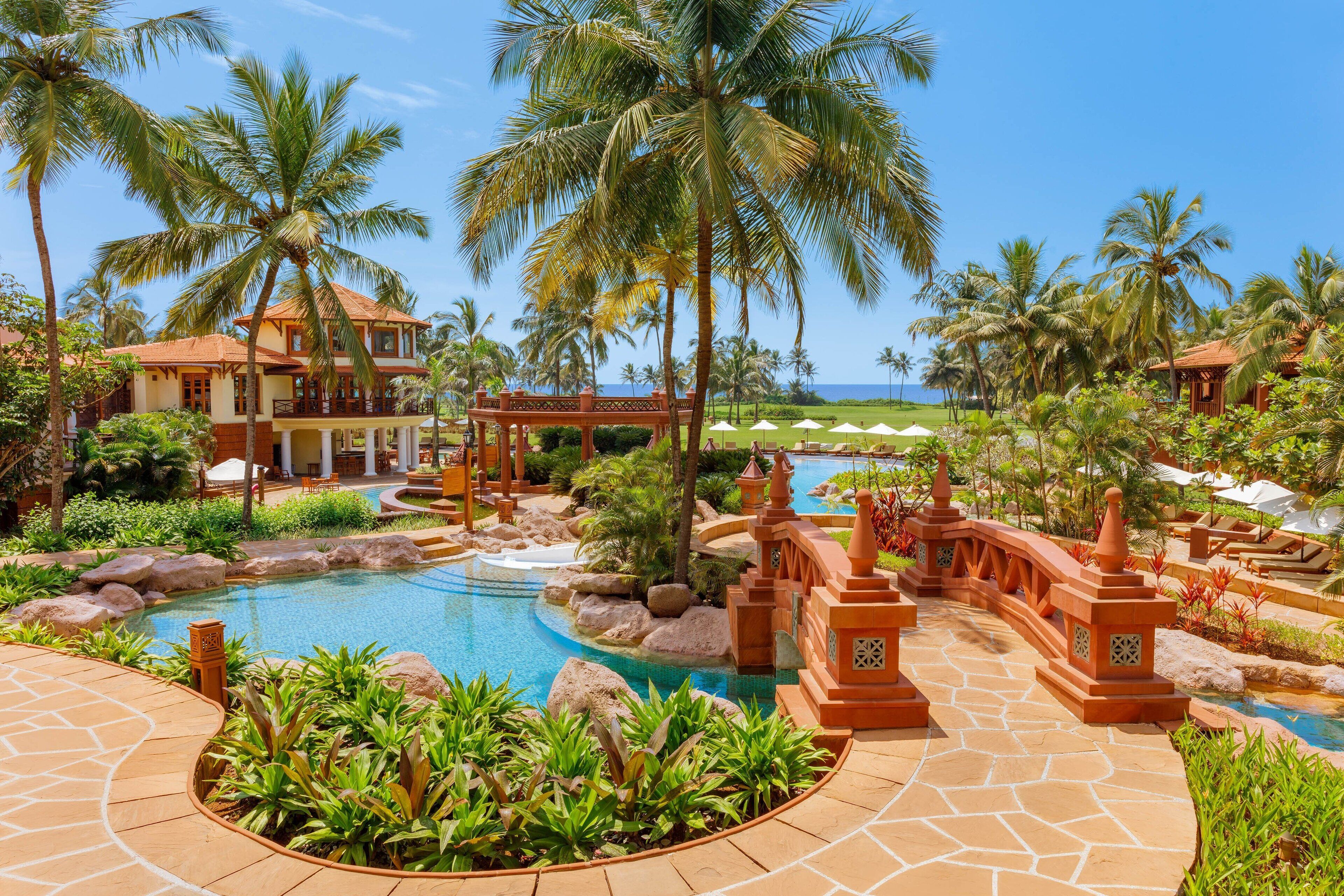 Un resort con piscina, palmeras y vista al océano.