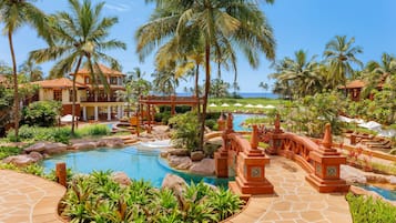 Un resort con piscina, palmeras y vista al océano.
