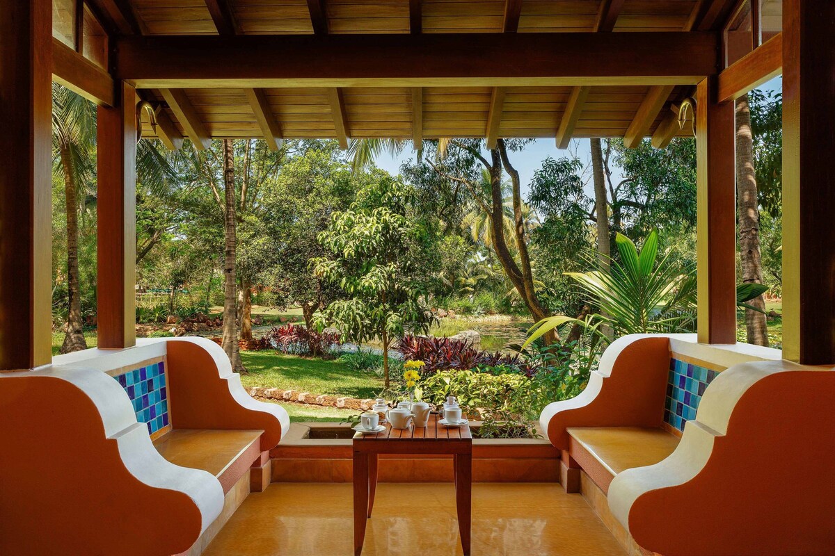 A covered outdoor seating area with a view of a lush garden.