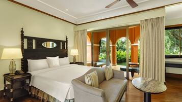 A hotel room with a large bed, a sofa, a small table, and a ceiling fan.