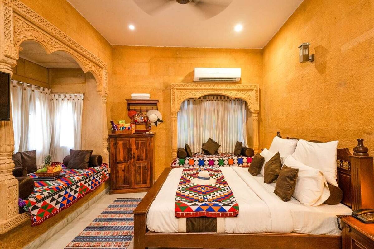 Une chambre de style traditionnel, dotée d’un grand lit, de deux petits lits, d’une armoire en bois et d’un miroir décoratif.