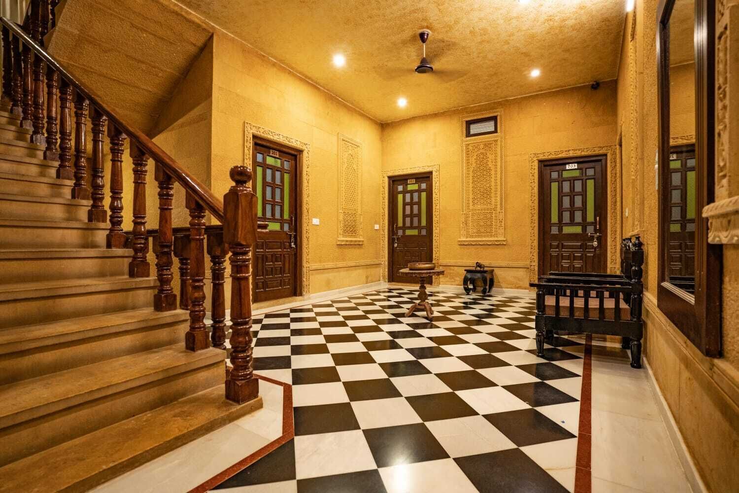 A hotel lobby with a checkered floor, wooden staircase, and traditional doors.