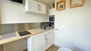 A compact kitchen with white cabinets, a stainless steel sink, a built-in microwave, and a small countertop.