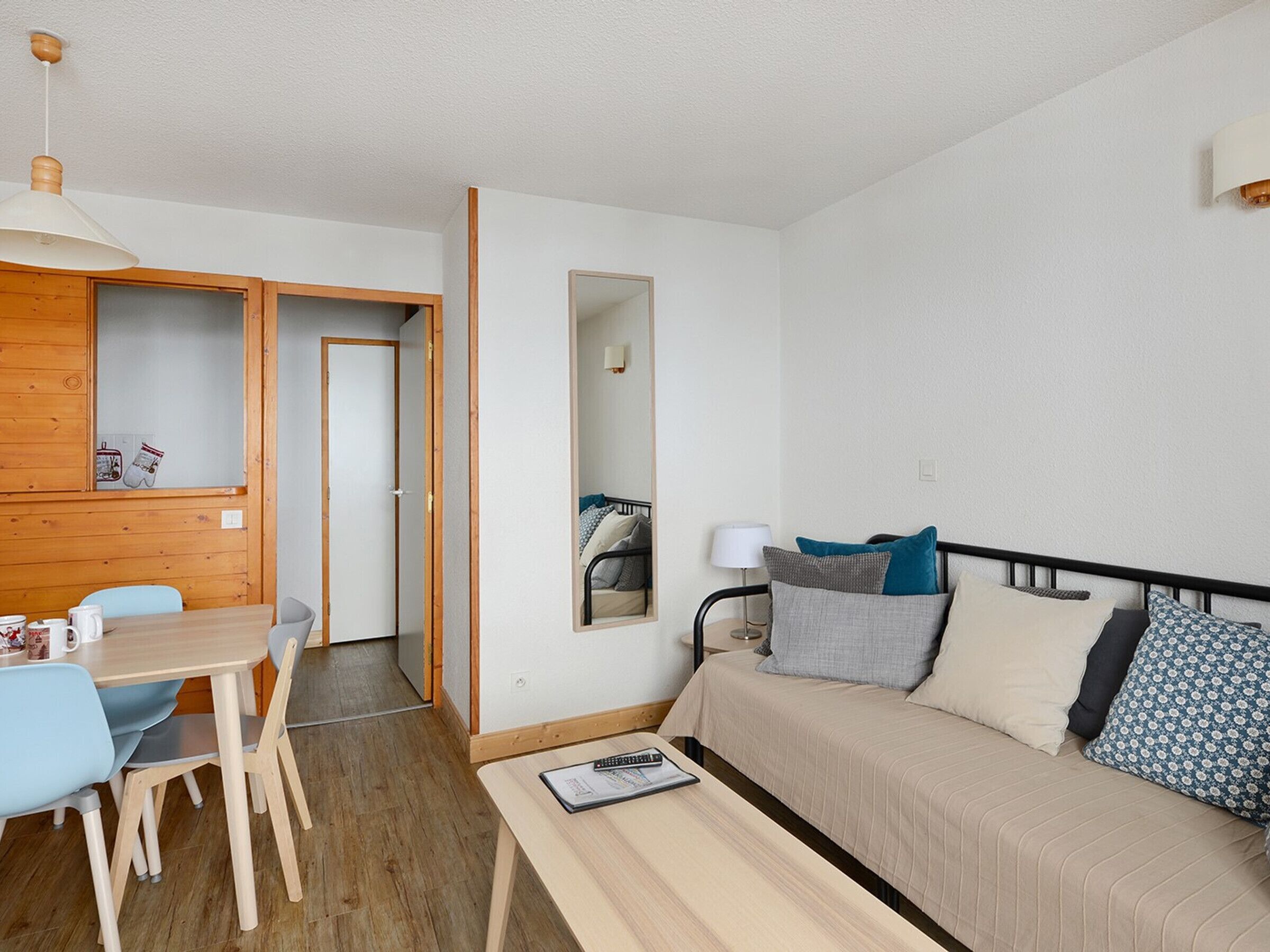 Il s’agit d’une petite pièce comprenant un lit, un bureau et une chaise. On y trouve également une armoire en bois avec un miroir, ainsi qu’une porte donnant sur une autre pièce.