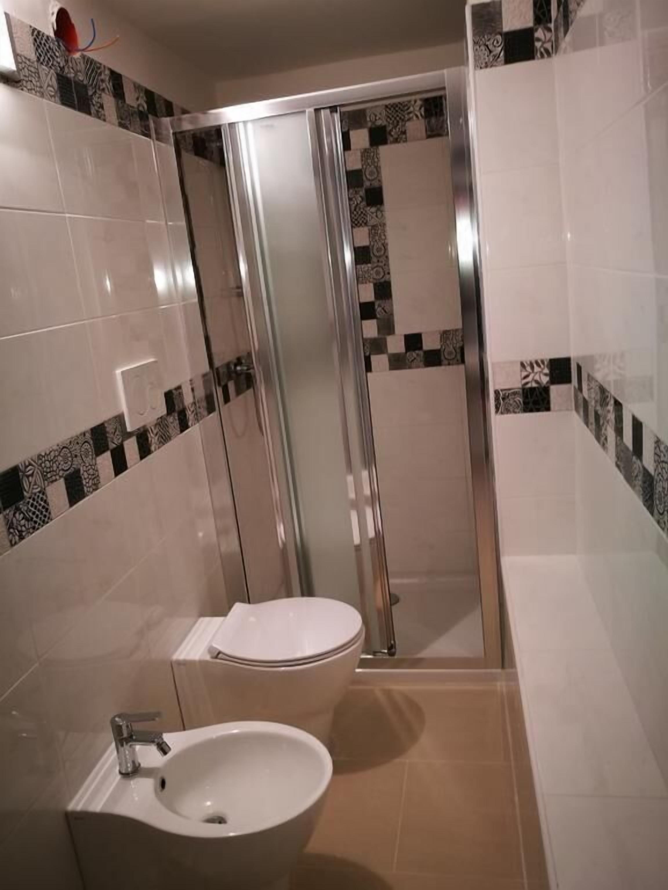 A modern bathroom with a glass-enclosed shower, a toilet, and a sink.