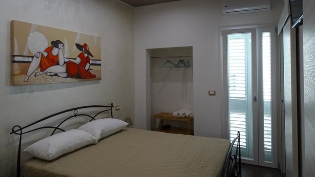 A bedroom with a bed, a painting on the wall, a wardrobe, and a window with blinds. - Nonna Ia (Parabita)
