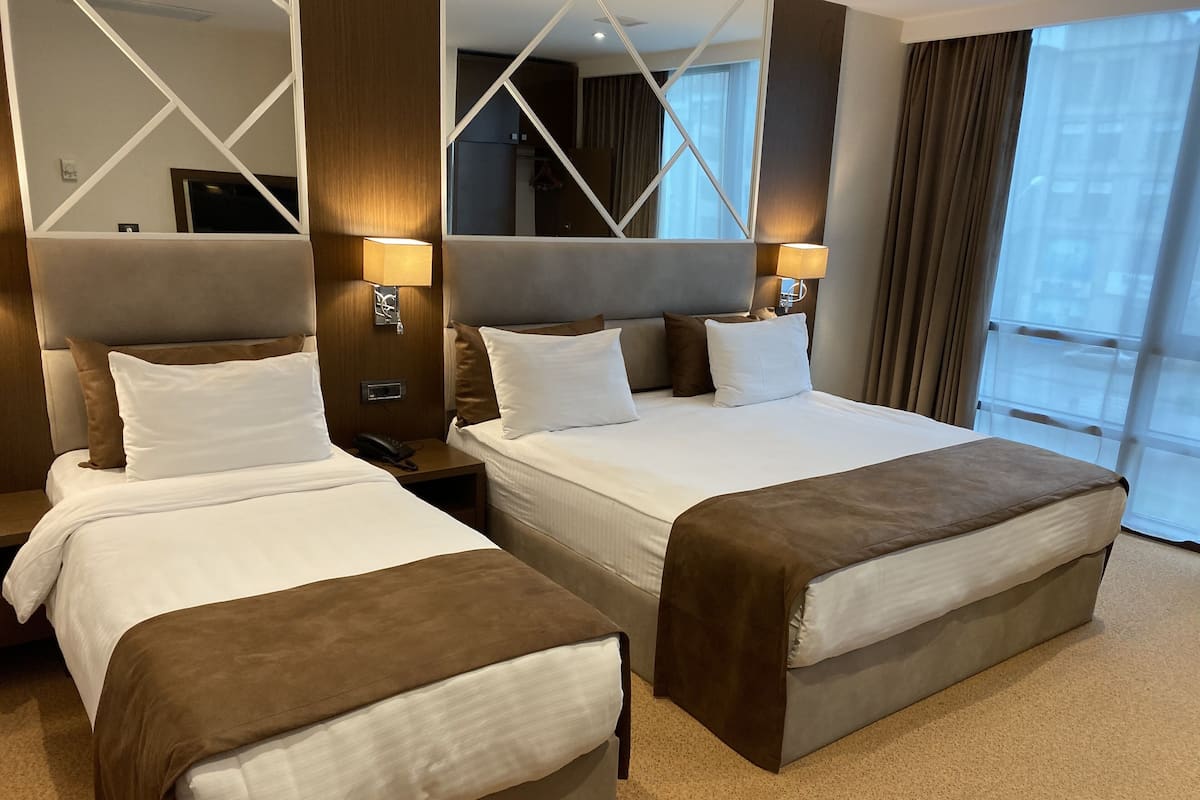 A hotel room with two beds, a large mirror, and a view of the city.