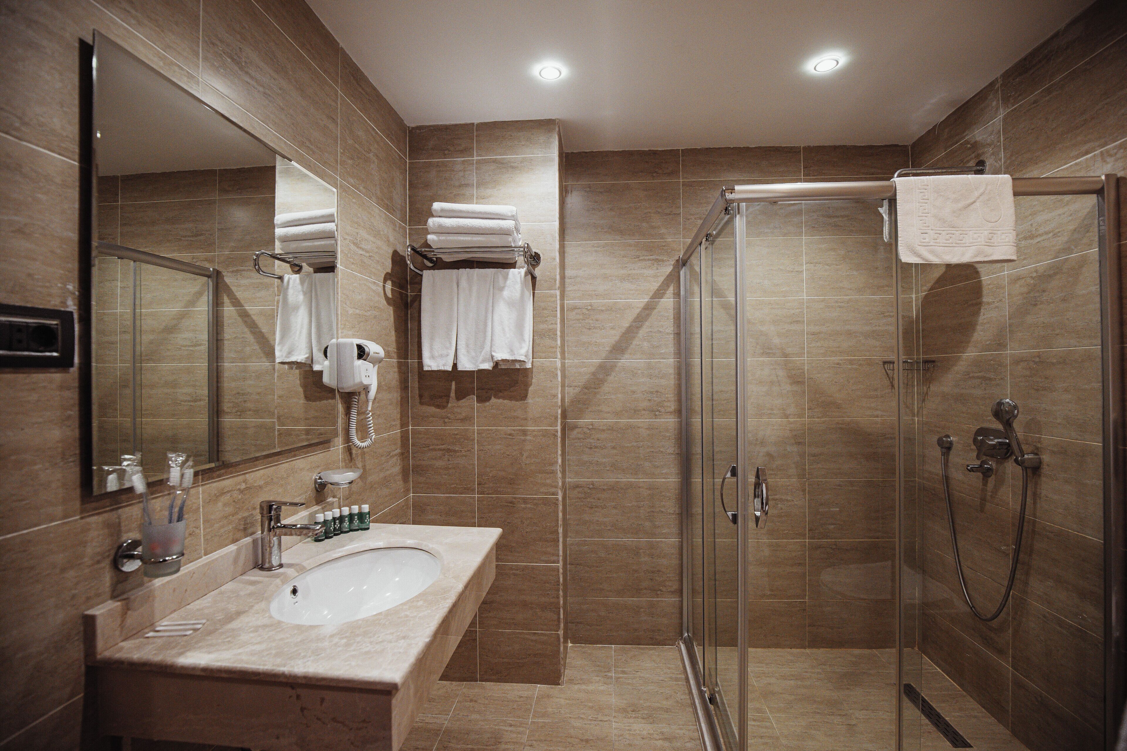 A modern bathroom with a sink, mirror, and glass-enclosed shower.