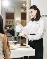 Iemand schenkt thee in bij een klant in een restaurant.